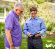 customer interacting on their front lawn, tech is holding a tablet